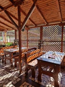 un pabellón de madera con bancos y mesas en un patio en Pensiunea Cota 1200 Piscul Negru, en Arefu