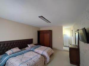 a bedroom with two beds and a flat screen tv at Sail Alhasa Tourist Resort-Tafila in At-Tafilah