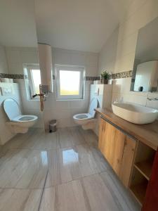 łazienka z 2 toaletami, umywalką i lustrami w obiekcie Villa Anchor w mieście Zadar