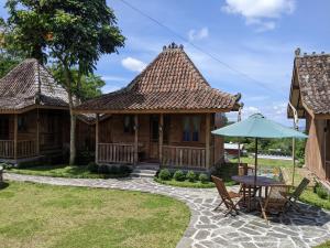 una casa con mesa, sillas y sombrilla en Le Desa Resort Syariah en Wonosobo
