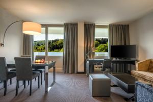 a living room with a table and a room with a desk at DoubleTree by Hilton Luxembourg in Luxembourg