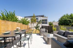 un patio con una valla de madera, una mesa y sillas en Nouveau - Maison à 15min du centre ville Nantes, en Orvault