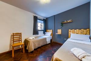 a room with two beds and a chair and a window at Viaggiato Nueva Cordoba in Cordoba