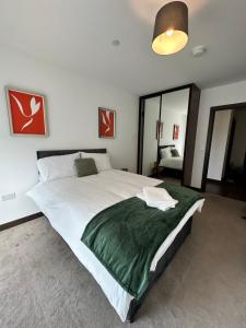 a bedroom with a large bed with a green blanket at Riverside Apartment in Peterborough