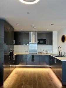 a kitchen with black cabinets and a wooden floor at Riverside Apartment in Peterborough