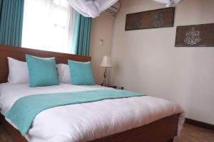 1 dormitorio con 1 cama grande con almohadas azules en Villa (2) Del Sol: Lakefront and Cruise Boat en Kisumu
