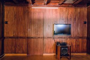 Cette chambre dispose d'un mur en bois et d'une télévision à écran plat. dans l'établissement Meenachil Creek Homestay, à Kottayam