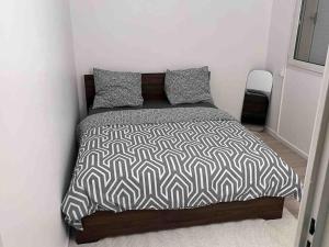 een slaapkamer met een bed met een zwart-wit dekbed bij Logement entier chambre+salon + jardin & terrasse in Les Ulis