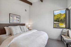 a white bedroom with a large bed and a window at Wildebrook in Stowe