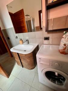 y baño con lavadora y lavamanos. en Villetta la Cinta, en San Teodoro