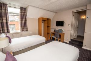 a hotel room with two beds and a tv at The George Inn in Selby