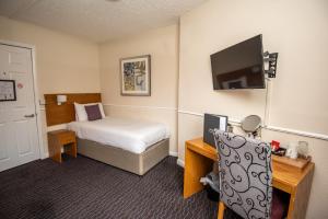 a hotel room with a bed and a desk with a television at The George Inn in Selby