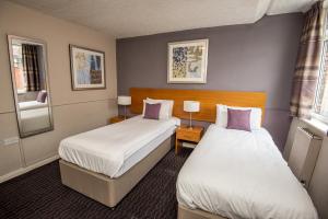 a hotel room with two beds and two windows at The George Inn in Selby