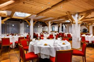 un comedor con mesas blancas y sillas rojas en Carlo Magno Hotel Spa Resort, en Madonna di Campiglio