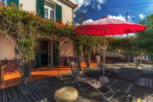 a patio with a red umbrella and chairs at Cozy Villa Flora by Holiday Rental Madeira in Estreito da Calheta