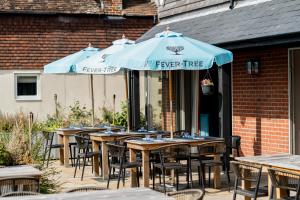 una fila de mesas con sombrillas azules en un patio en The Binsted Inn en Alton