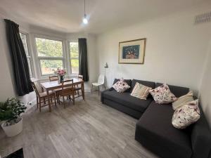 a living room with a black couch and a table at Modern 2 bedroom flat, SE6 in Catford