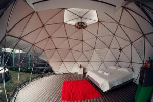 a bedroom in a dome tent with a bed and a red rug at Paraiso Tropical Glamping in San Antonio