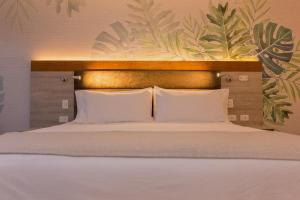 a bedroom with a bed with white pillows and a wall at Termales El Otoño in Manizales