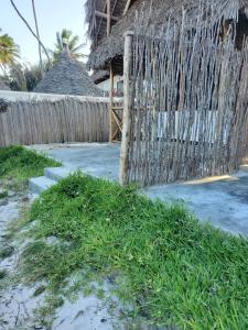 a fence on the beach with some grass at Kibwana Village Bungalows in Matemwe +7 photos