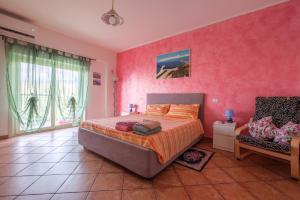 テルメ・ヴィリアトーレにあるMeizon Siciliaのピンクの壁のベッドルーム(ベッド1台、椅子1脚付)
