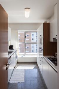 a kitchen with white cabinets and a large window at FLH Alta Lisboa Brightly Flat in Lisbon