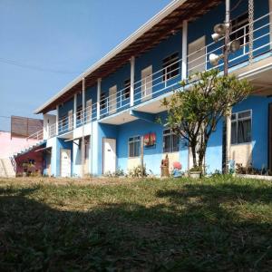 a blue and white building with a tree in front of it at Pousada Flor de Liz in Angra dos Reis