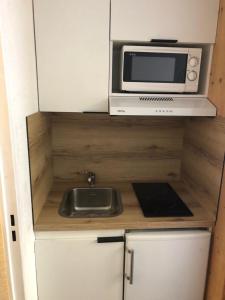 a small kitchen with a microwave and a sink at Studio Tignes Val Claret in Tignes