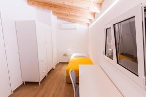 Cette petite chambre comprend un lit jaune et des armoires blanches. dans l'établissement White Home, à Castellammare del Golfo
