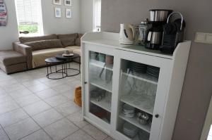 a kitchen with a white cabinet filled with dishes at Kustverhuur, Park Schoneveld, Stern 254 in Breskens +19 photos