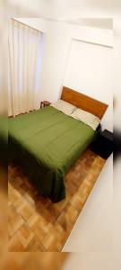 a bed with a green comforter in a room at Antarki Guest House in Cusco