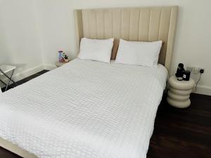 um quarto com uma cama branca com lençóis e almofadas brancos em Newly refurbished 1-Bed Apartment in Croydon SE25 em Londres