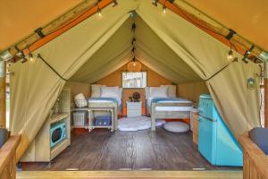 a tent with two beds and a microwave in a room at Hive Check - Safari Tent - BeeWeaver Honey Farm in Navasota