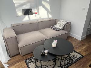 Newly refurbished 1-Bed Apartment in Croydon SE25 في لندن: غرفة معيشة مع أريكة وطاولتين