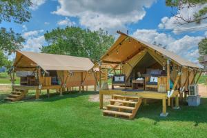a large tent with benches in the grass at BeeWeaver Luxury Glamping - Idyllic Hive Check in Navasota