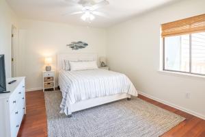 a white bedroom with a bed and a window at Oceanfront Condo with Pool - Salty Hammocks A6 in Carolina Beach +23 photos