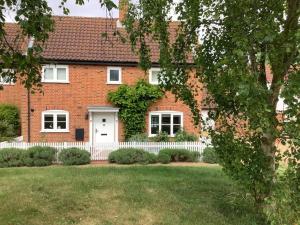 a brick house with a white fence and a yard at Peaceful house ideal for dogs lovely location in Aldeburgh
