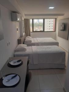 um quarto de hotel com duas camas e uma mesa com pratos em Manaíra Apart Hotel em João Pessoa