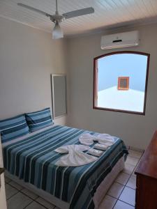 a bedroom with a bed with blue pillows and a window at Casa do Éden in Paraty