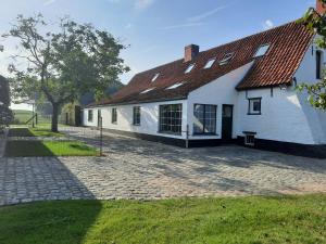 a white house with a red roof and a brick driveway at B&B Den Bruynen Bergh in Beernem