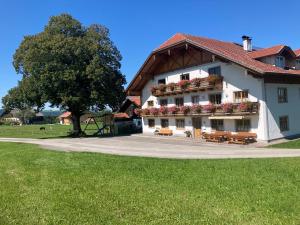 a large white building with benches and a tree at Biohof-Feichtinger in Zell am Moos