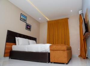 a bedroom with a large bed and a yellow curtain at E&T Luxury Apartments in Uyo