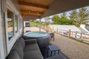 una bañera de hidromasaje al lado de una casa en Luxury Log Cabin with Private Hot Tub & Sea Views, en Letterkenny
