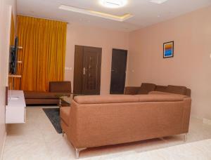 E&T Luxury Apartments في أويو: غرفة معيشة مع أريكة وستارة صفراء