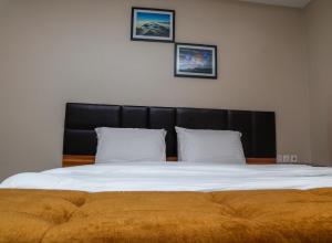 a large bed with a black headboard and two pillows at E&T Luxury Apartments in Uyo