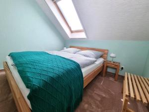 a bedroom with a bed with a green blanket on it at Ferienwohnung Am Helderbach 