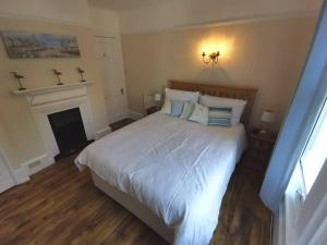 ein Schlafzimmer mit einem weißen Bett mit Kissen und einem Kamin in der Unterkunft Beautiful gate house a 4 minute walk from beach in Bersted