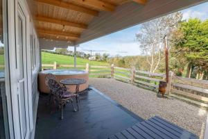 porche con bañera, mesa y sillas en Luxury Log Cabin with Private Hot Tub & Sea Views, en Letterkenny