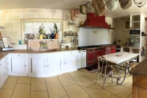 une cuisine avec des placards blancs et une table. dans l'établissement * Ancien domaine viticole de la Brandette *, à Gaillan-en-Médoc