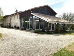 un bâtiment avec de nombreuses fenêtres sur une allée en gravier dans l'établissement * Ancien domaine viticole de la Brandette *, à Gaillan-en-Médoc